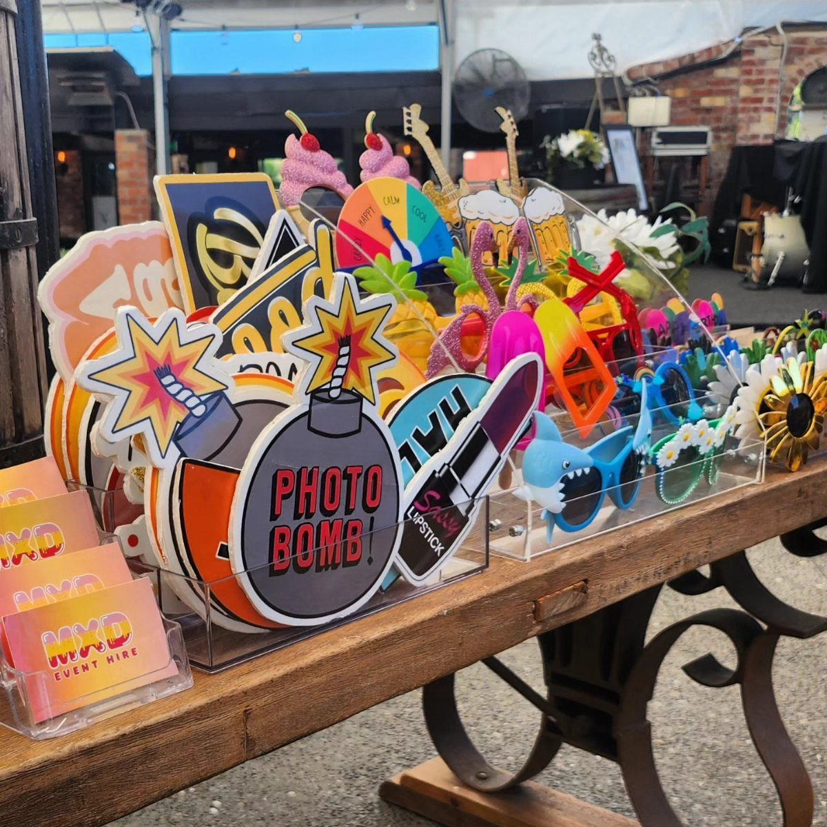 Colorful photo booth props including a photo bomb cutout on a wooden table.