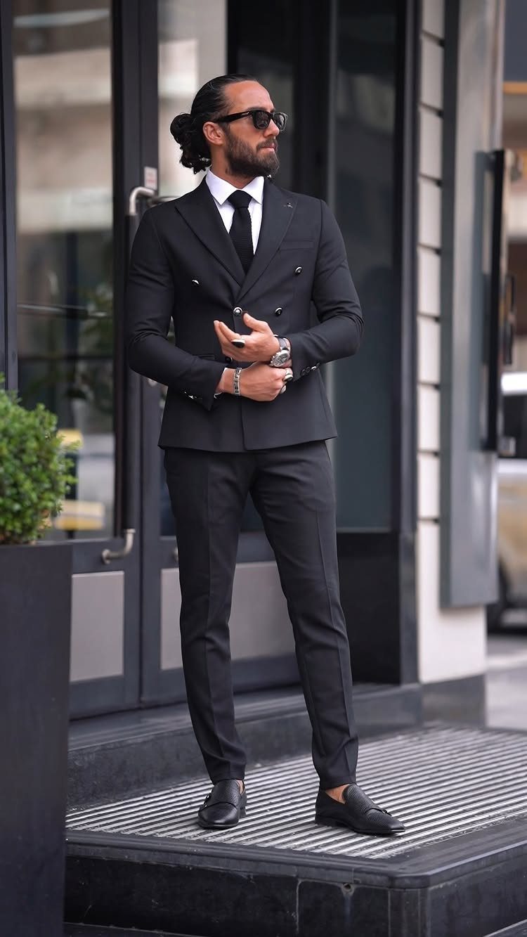 Man in a black double-breasted suit with a white shirt and black tie.