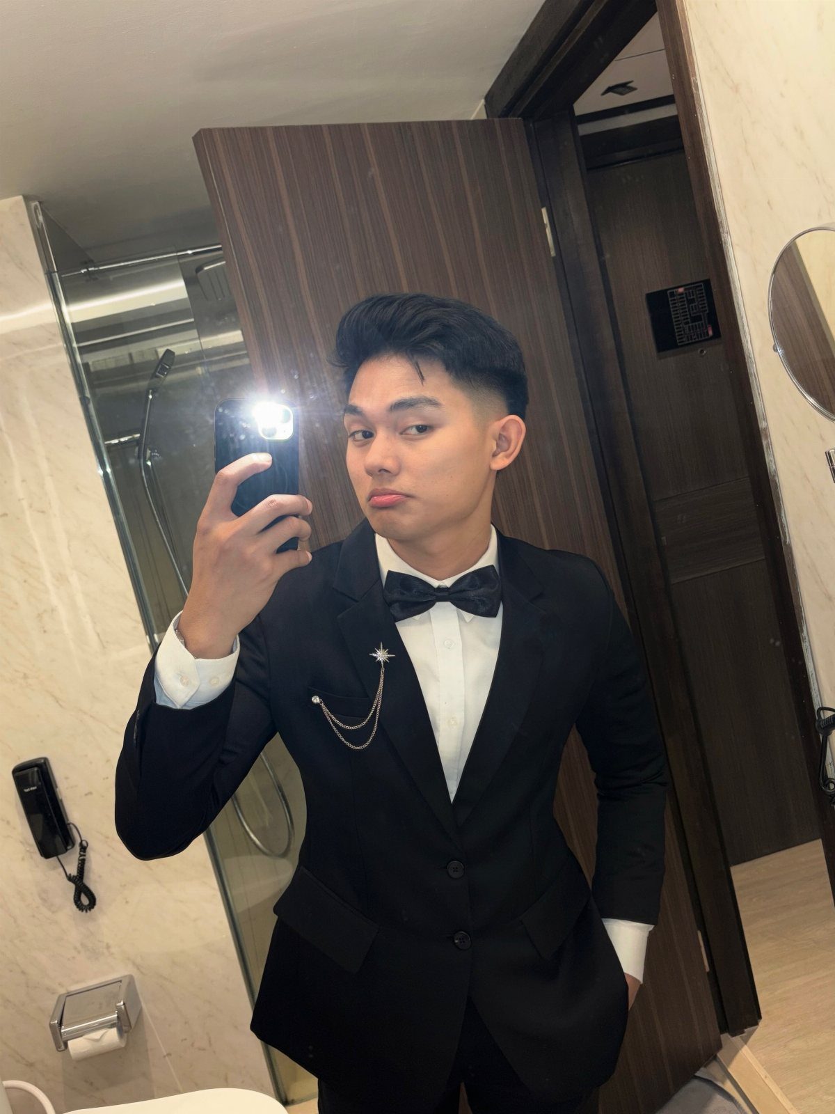 Young man in a black suit and white shirt with a black bow tie.
