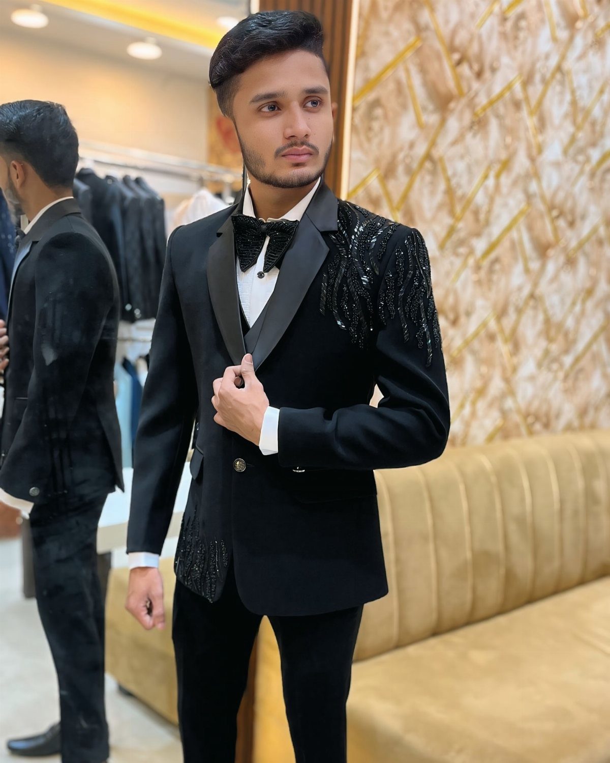 Young man wearing a black tuxedo with sequins, bow tie, and white shirt.