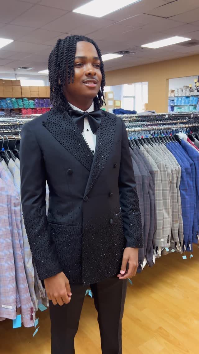 Young man wearing a black double-breasted prom suit with a black bow tie.