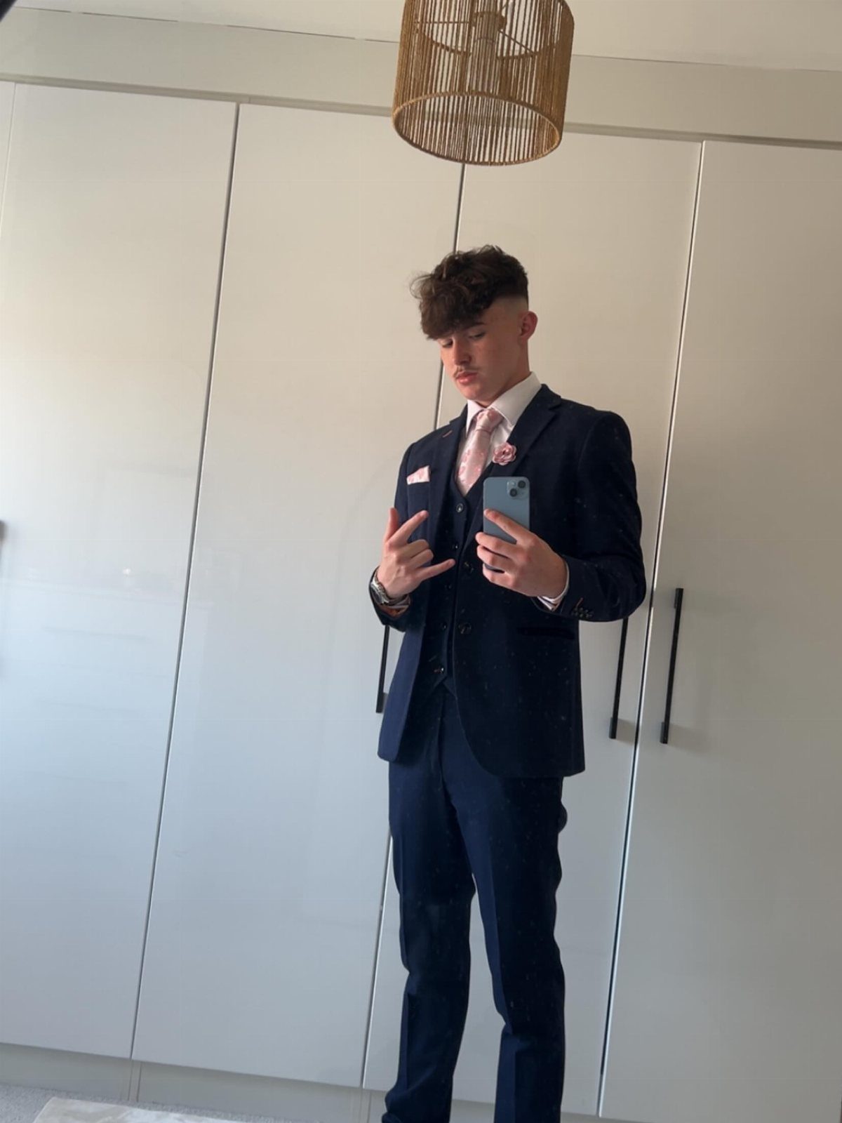 Young man in a navy blue three-piece suit with a pink tie.