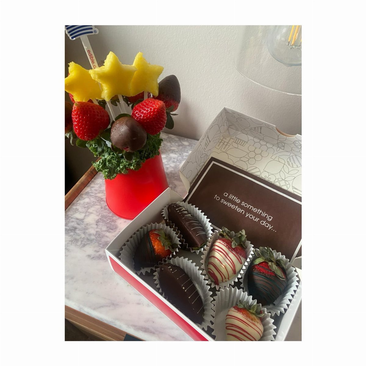 Chocolate-covered strawberries in a box and a fruit bouquet with pineapple stars.
