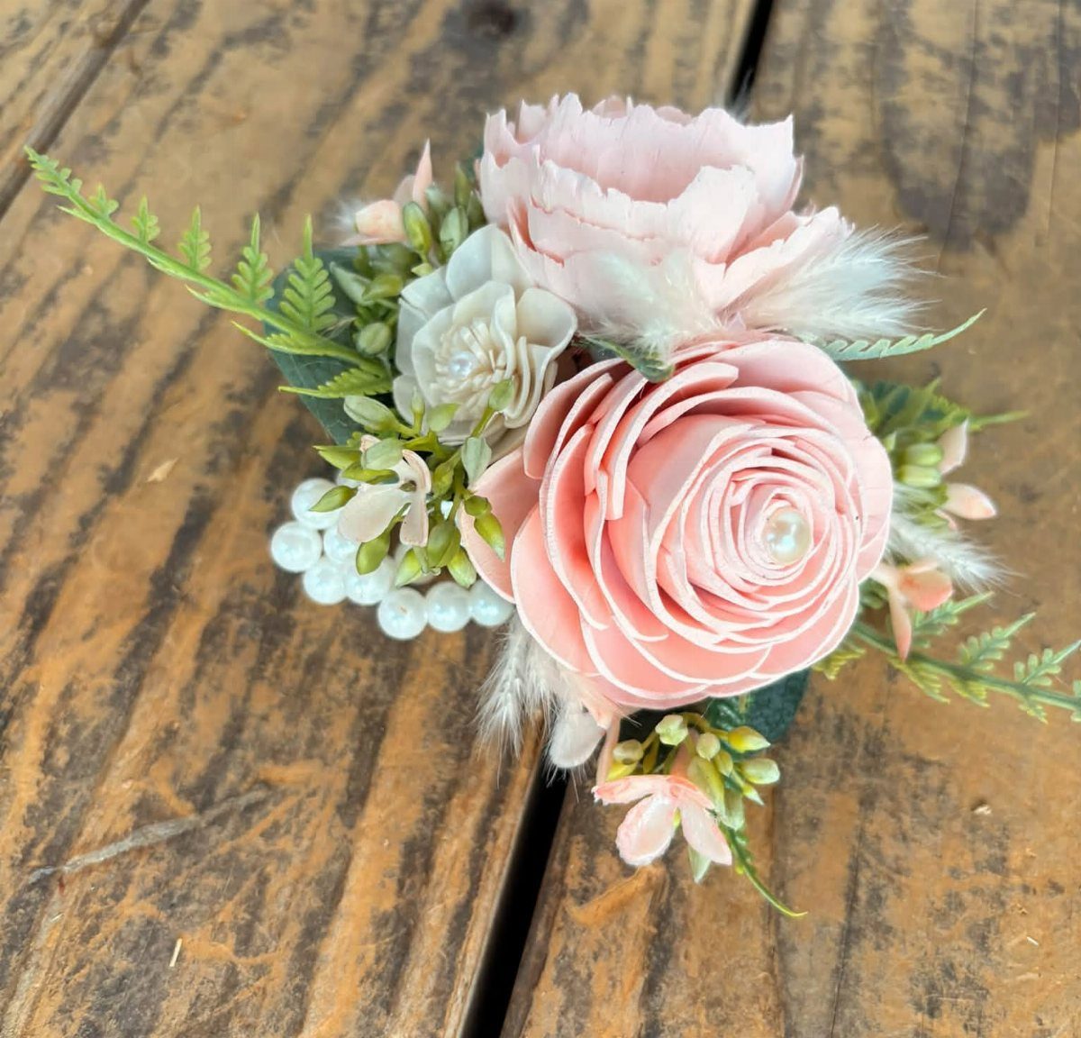 Pink and white wooden flower boutonniere with pearls on a rustic wooden background