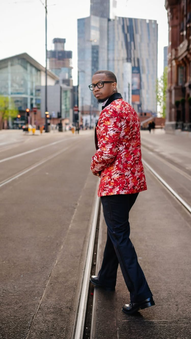 Man in a red floral patterned tuxedo jacket standing on a city street