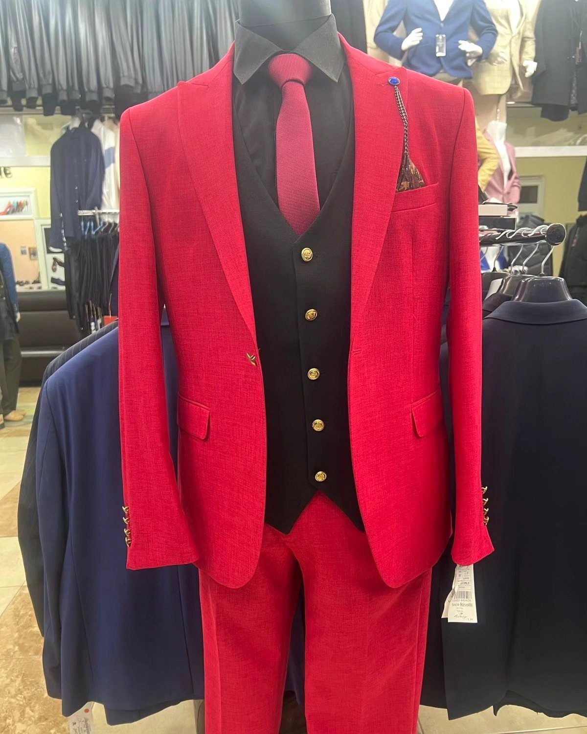 Red suit jacket and trousers on a mannequin with black vest and tie.