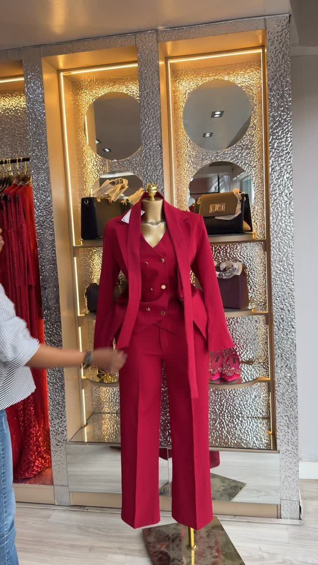 Red three-piece suit on a mannequin in a boutique with gold mirrors.