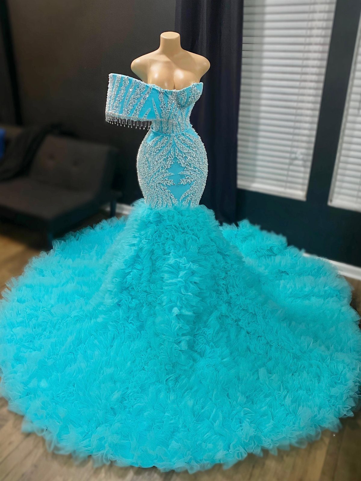 Cyan blue gown with beaded bodice and voluminous ruffled tulle skirt on mannequin