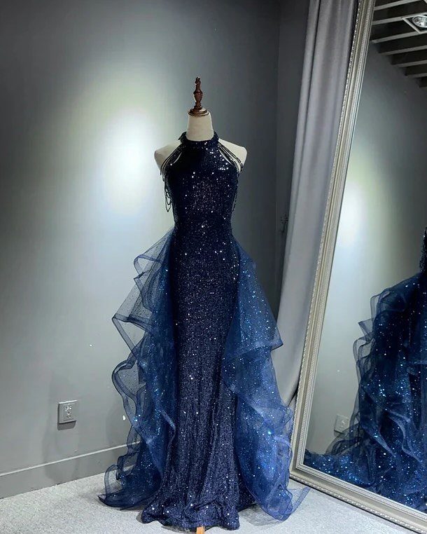Navy blue sequined halter gown with a ruffled tulle overskirt on a mannequin