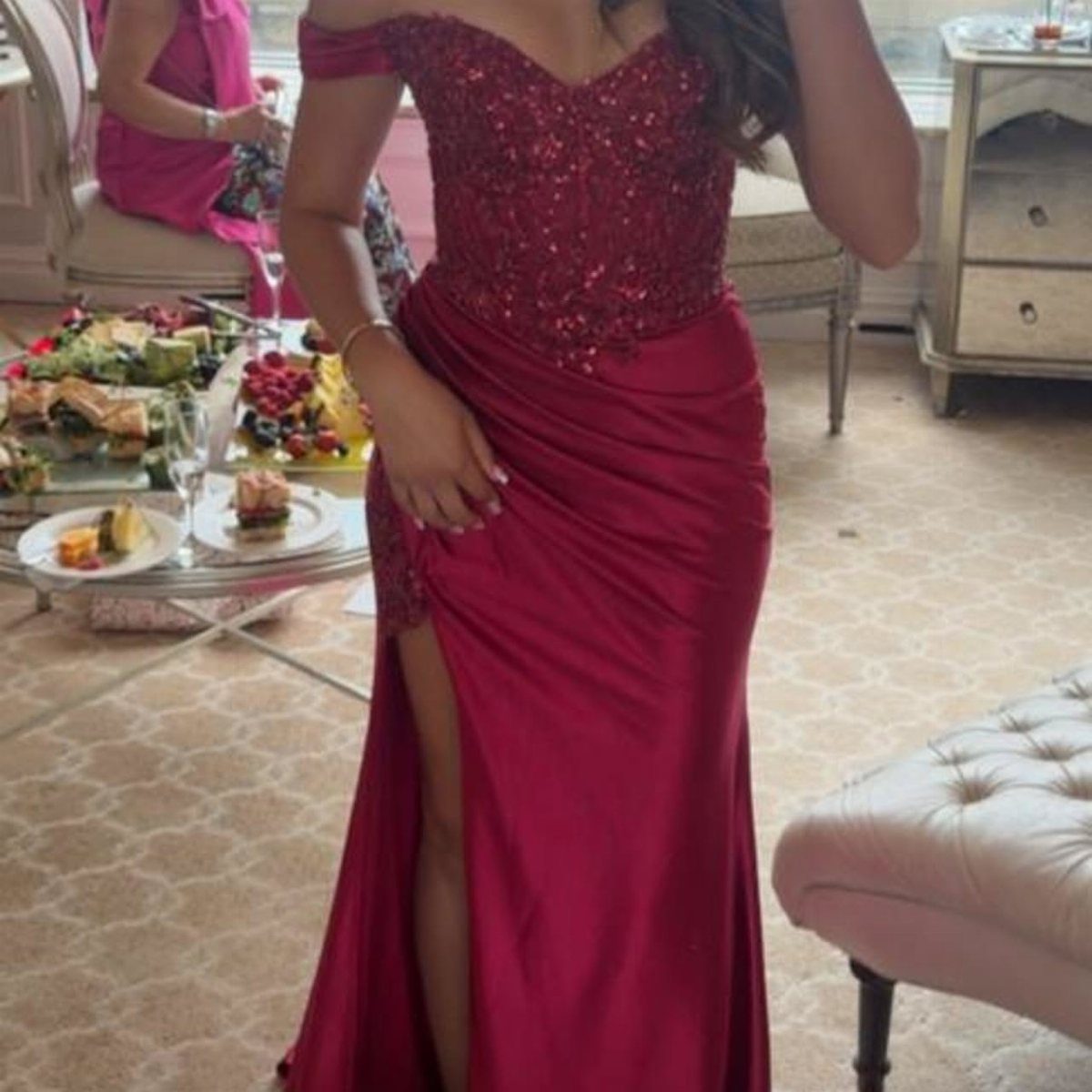 Person wearing a red satin gown with a beaded bodice and high slit.