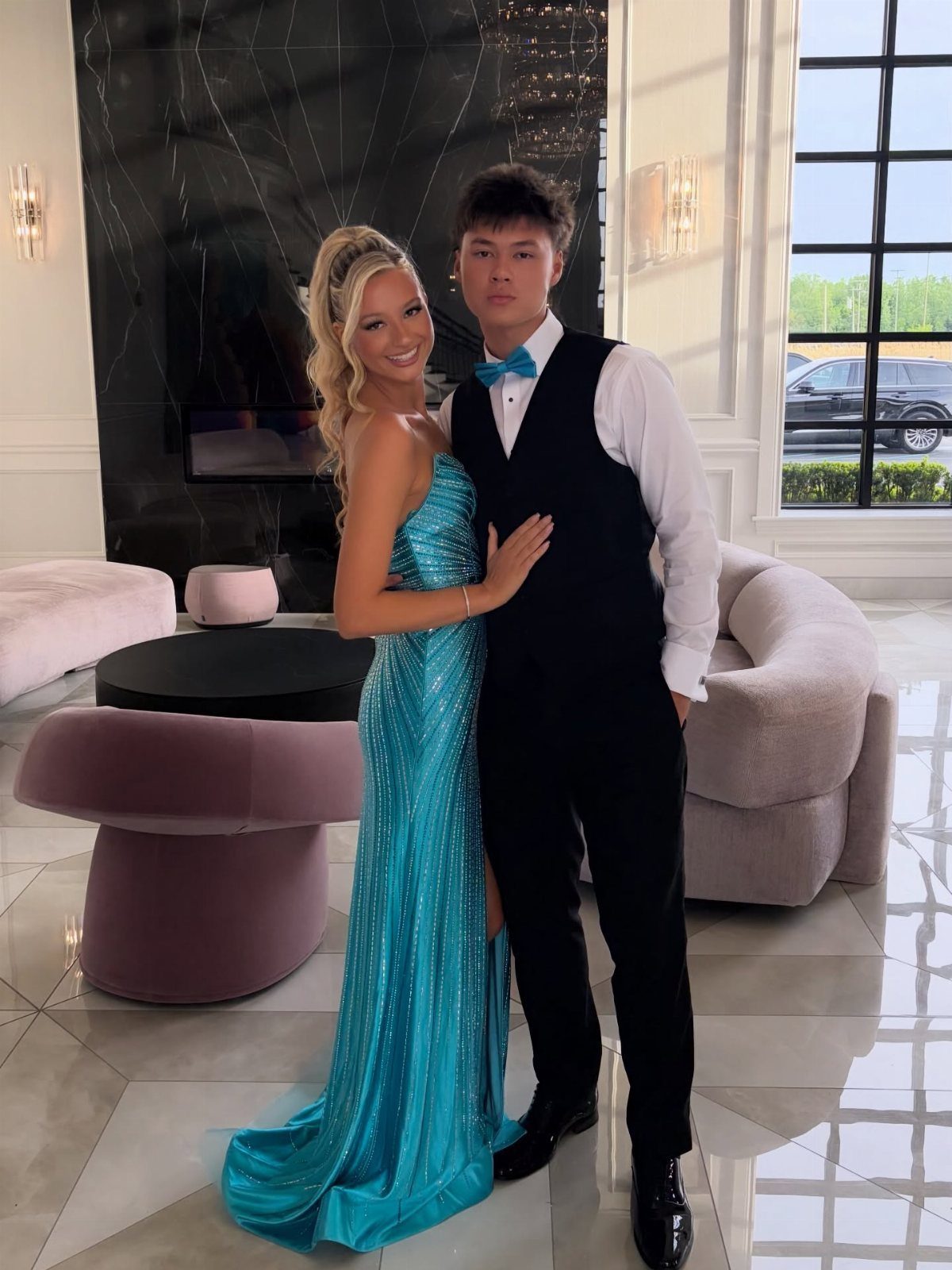 Young couple posing, woman wearing a long shimmering teal sequined gown.