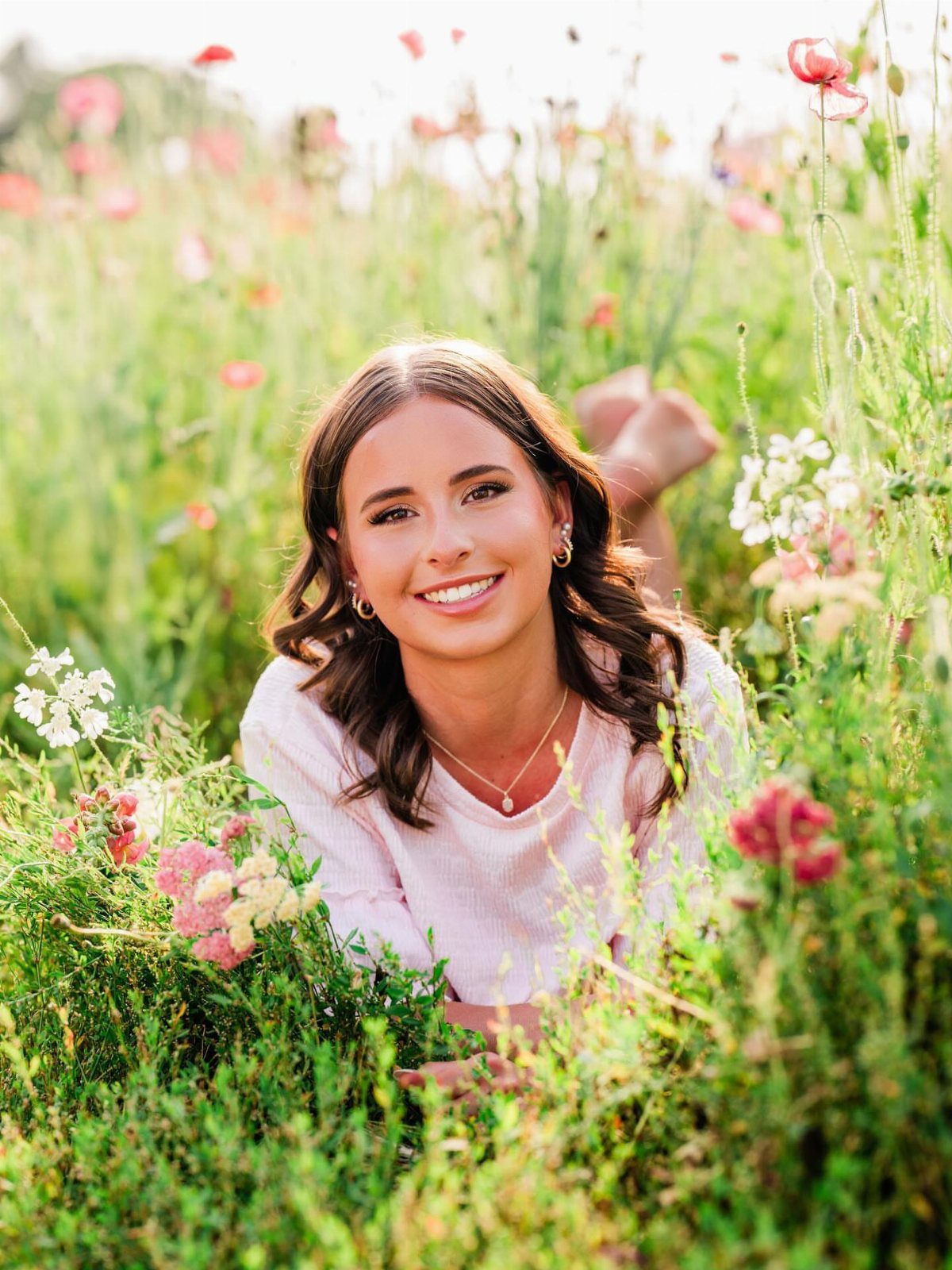 Smiling young woman lying on her stomach in a wildflower field.