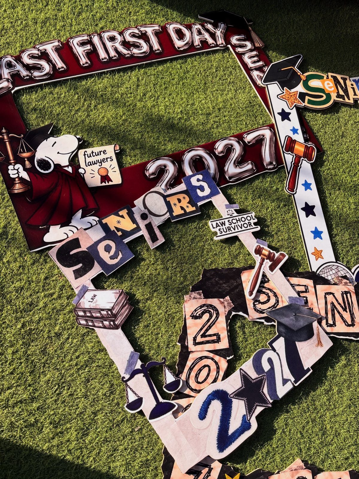 Decorated graduation frames with years and law symbols resting on green grass.