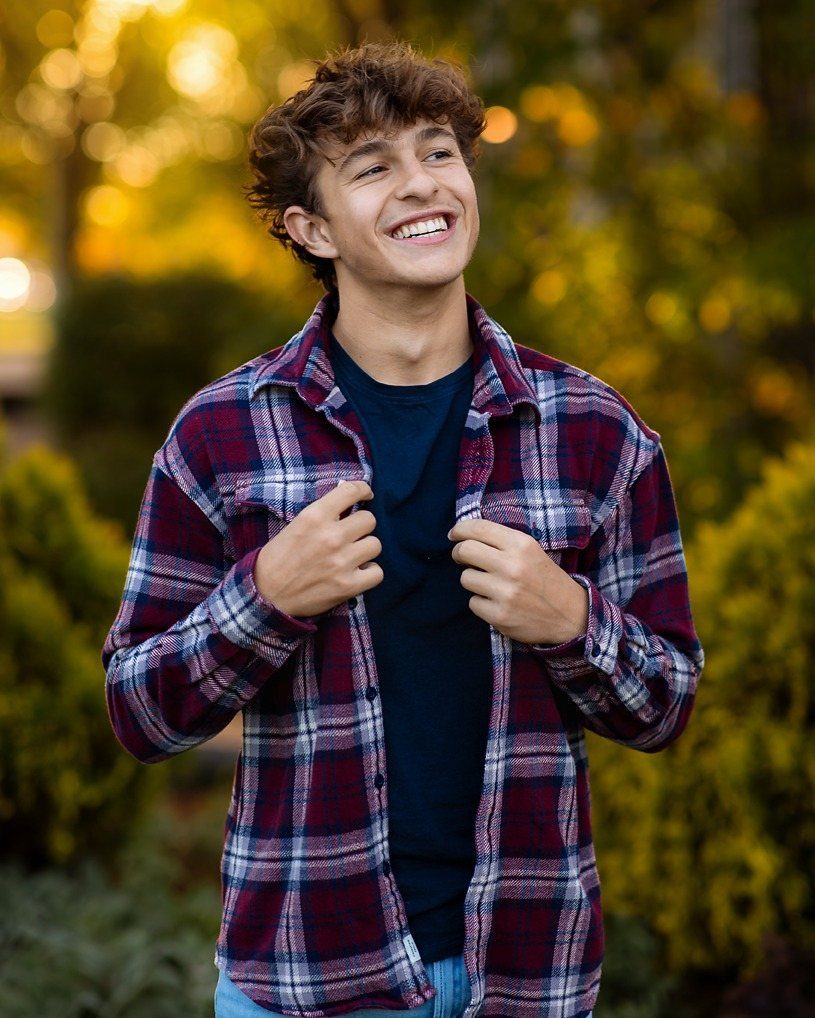 Smiling young man wearing a red plaid flannel shirt over a navy t-shirt.