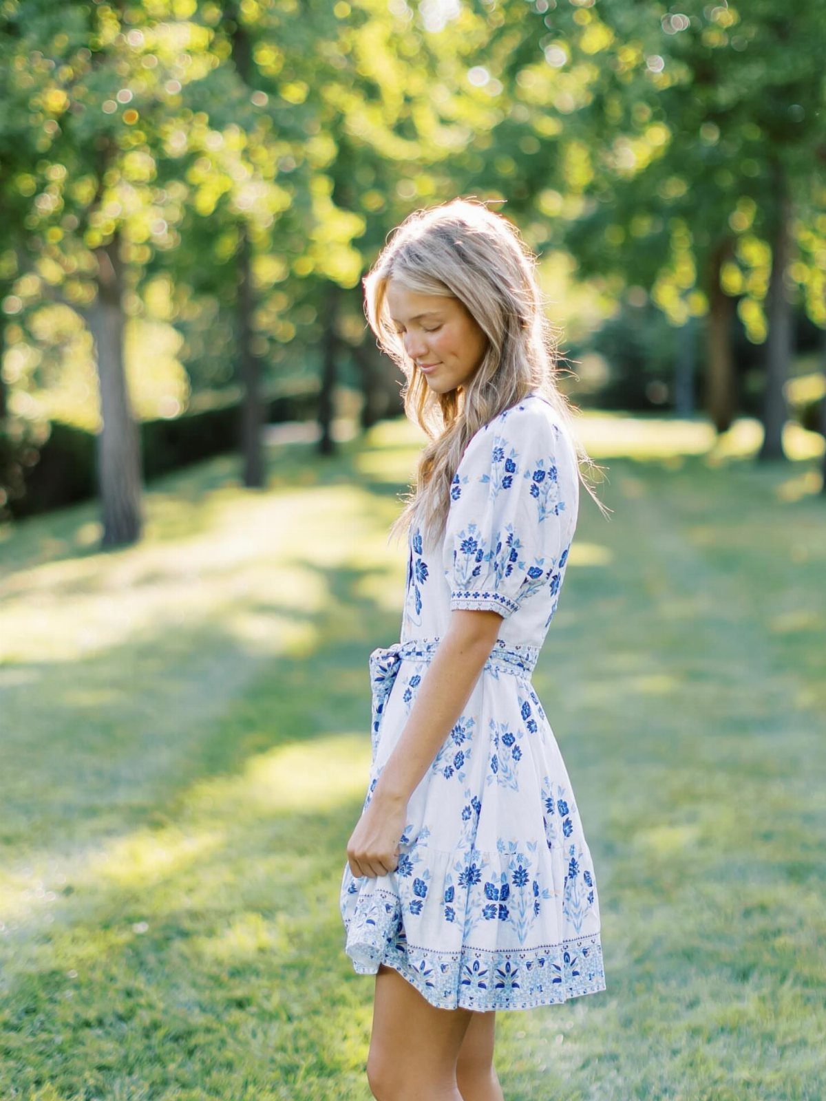 Young woman in a white and blue floral puff sleeve mini dress outdoors.