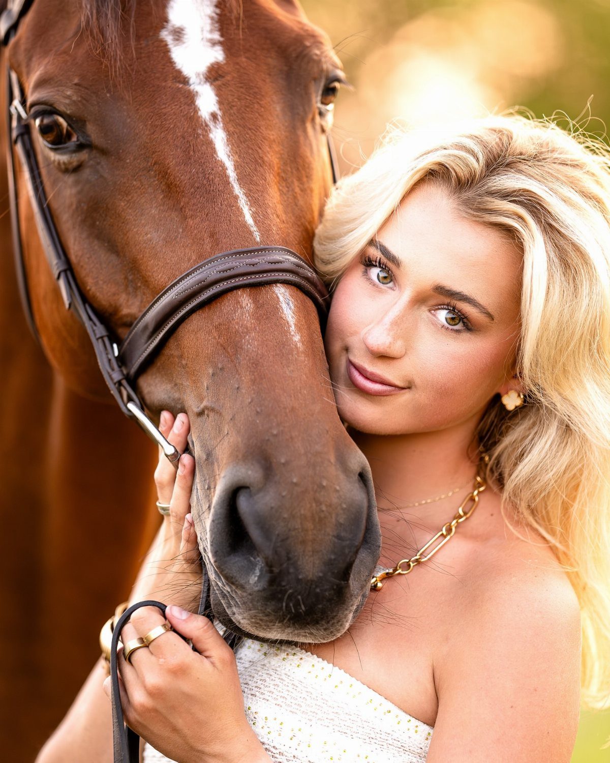 Blonde woman leaning her face against a brown horse with a white blaze.