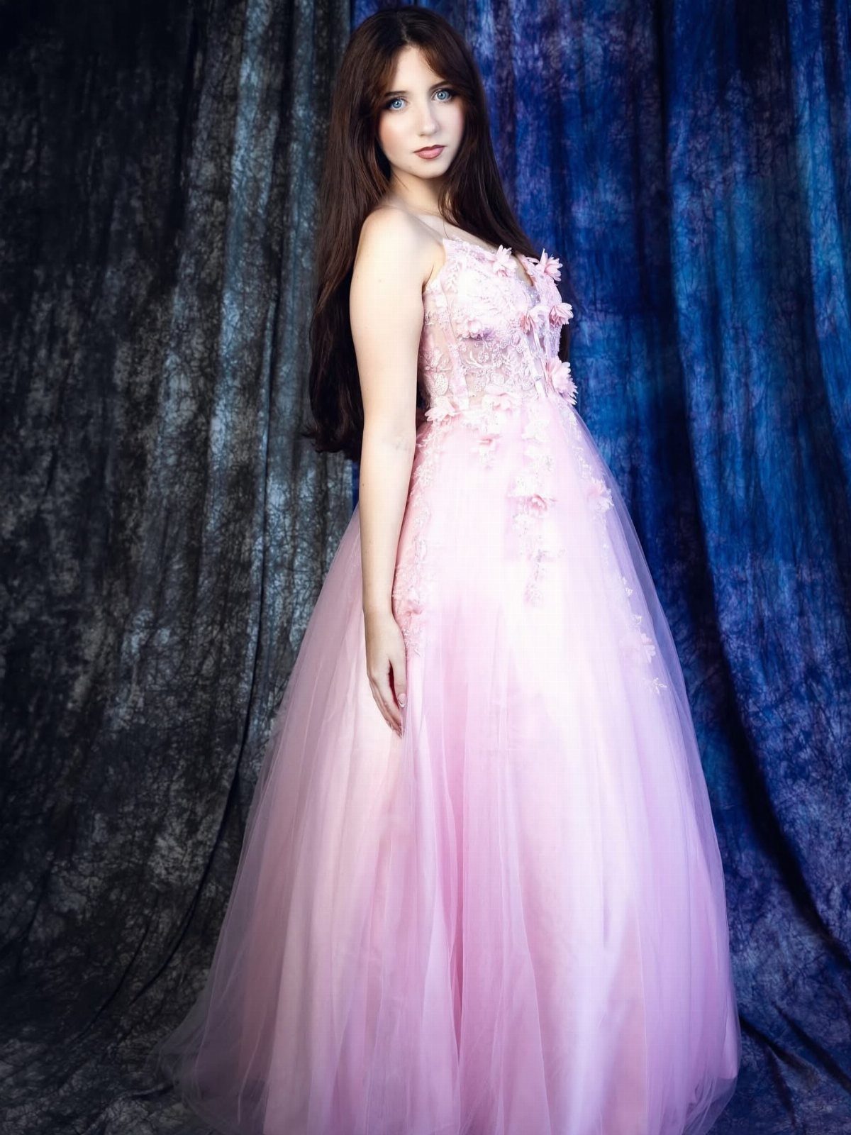 Young woman in a pink floral ball gown with a full tulle skirt.