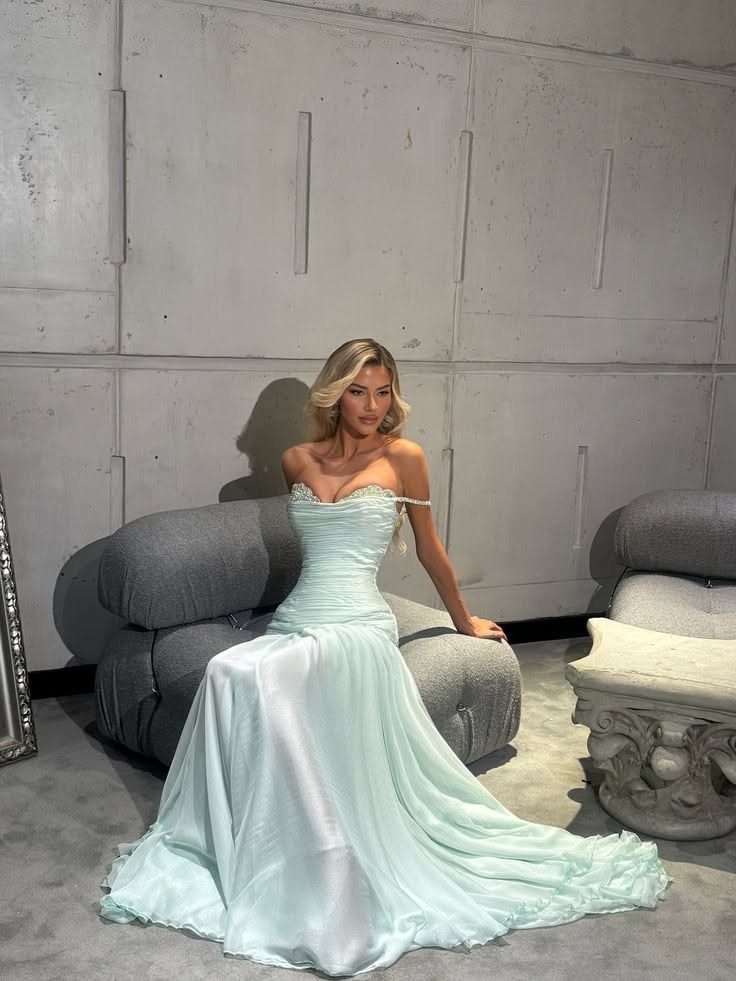 Woman in a light mint green floor-length satin strapless gown posing indoors.