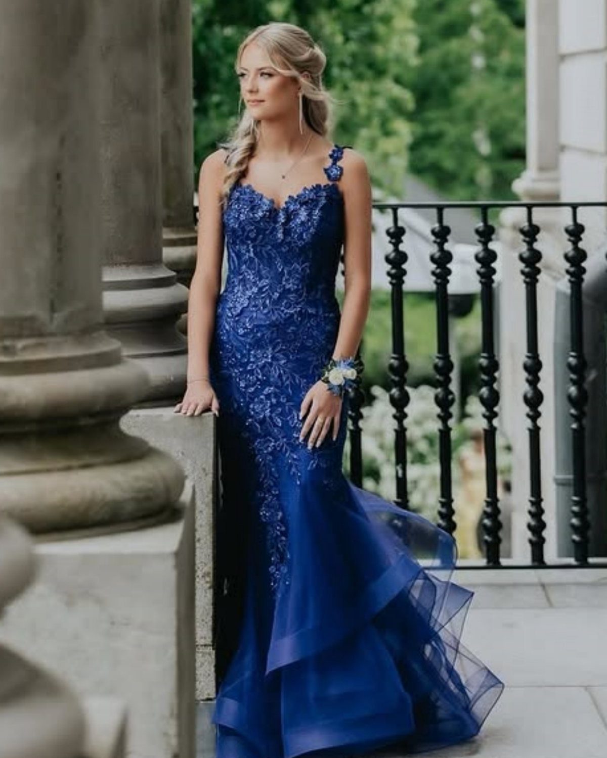 Woman in a royal blue mermaid gown with lace and ruffled tulle skirt.