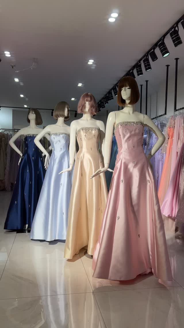 Four strapless satin prom gowns in blue, champagne, and pink on store mannequins.