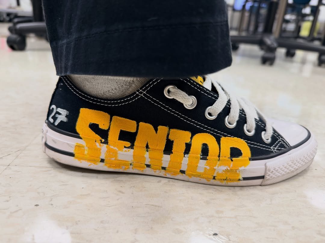 Black canvas sneaker with yellow painted SENIOR text and white number 27.