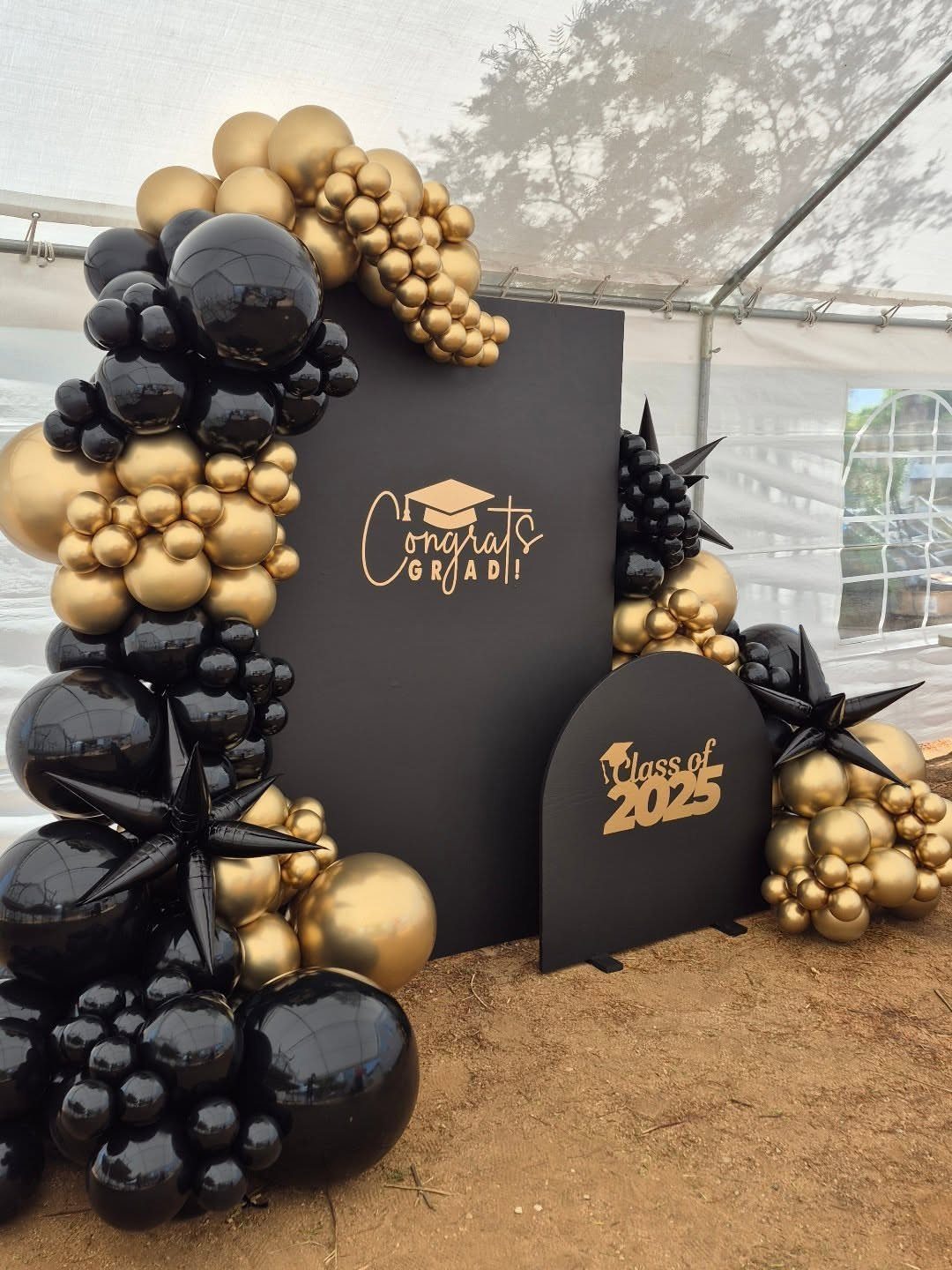 Graduation backdrop with black and gold balloon arches and Class of 2025 signage.