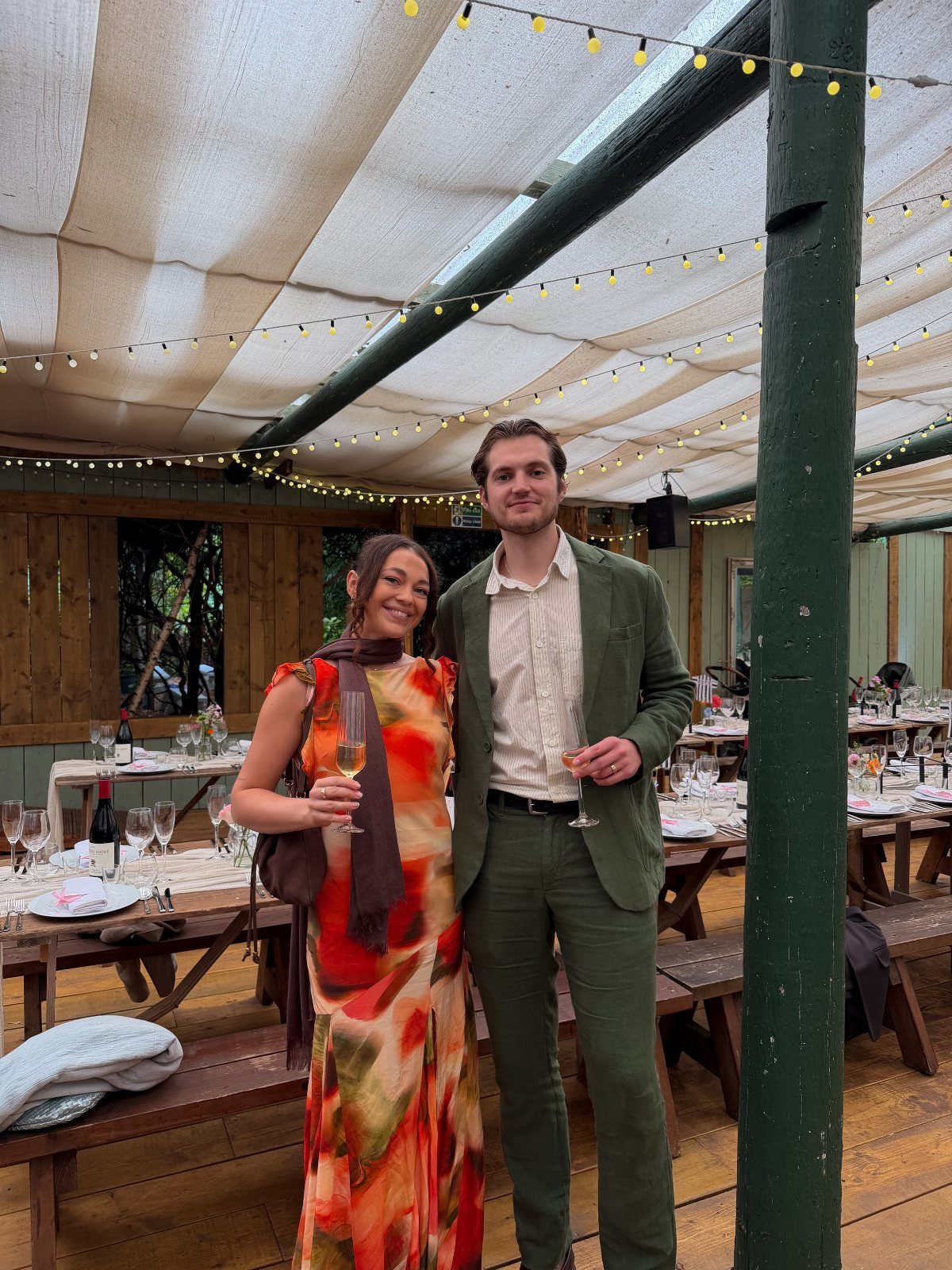 Man in green suit and woman in colorful maxi dress posing at wedding.