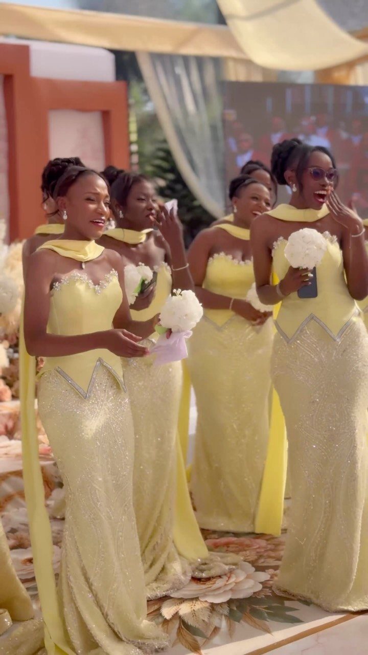 Four women in shimmering yellow floor-length wedding party dresses holding white bouquets.