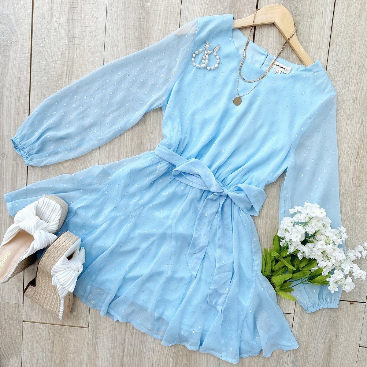 Light blue short dress with white wedge sandals and flowers on wooden floor