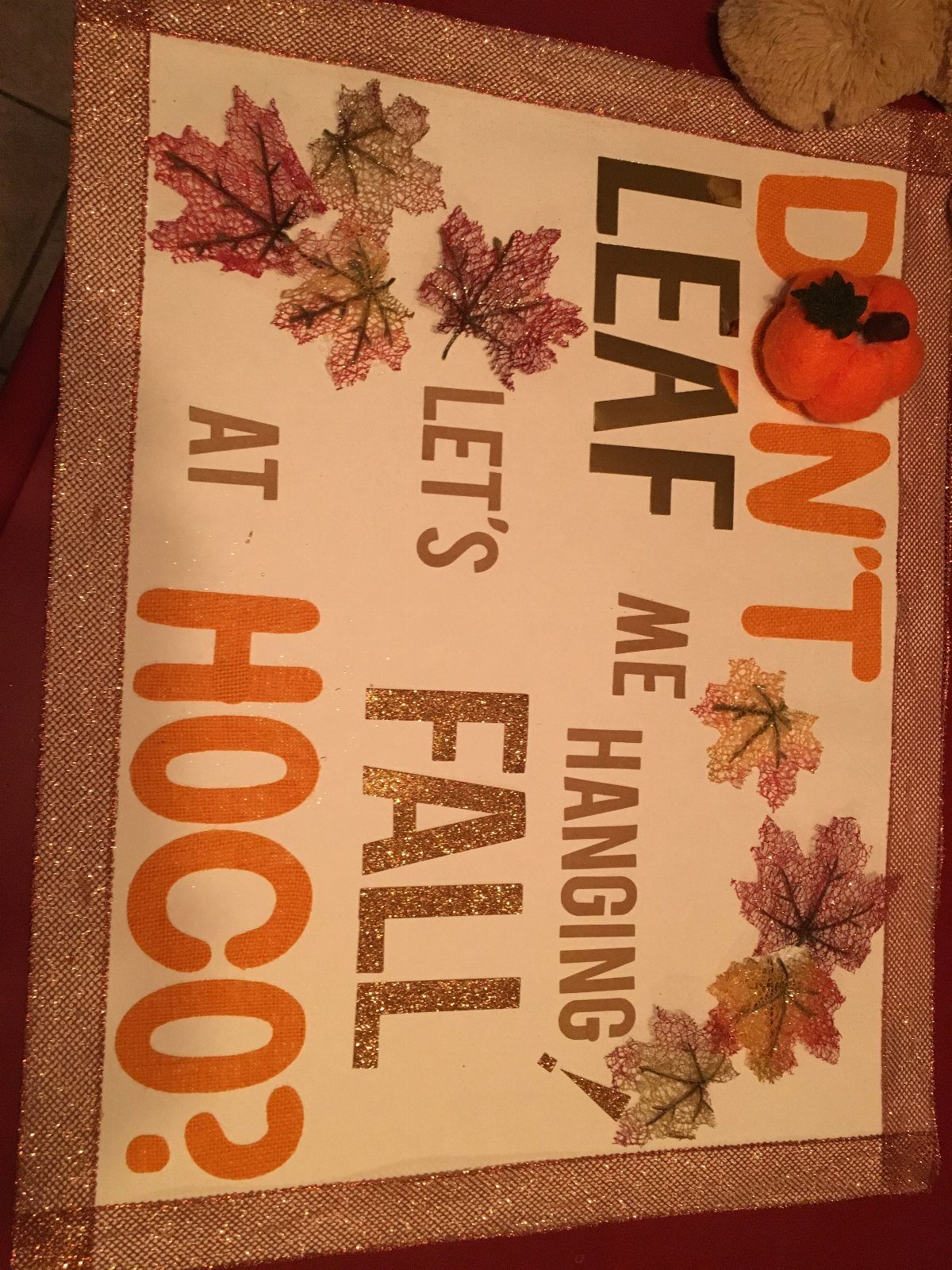 Homecoming proposal poster with autumn leaf cutouts and orange glittery text.